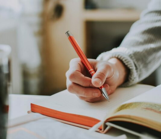 정부 “국민 지지로 의대 증원 이뤄져…의료개혁 안착 노력할 것” person holding on red pen while writing on book