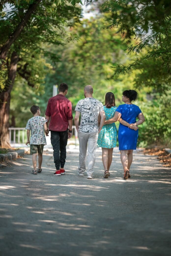 Photo by Some Tale man in red t-shirt and gray pants holding hands with boy in blue t-shirt