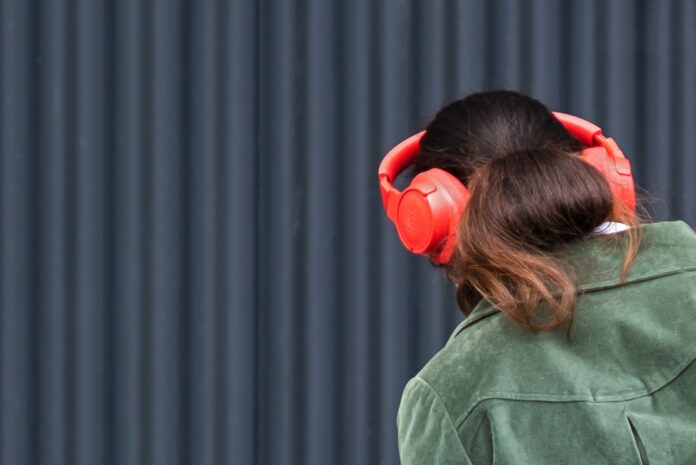 Photo by Lucas van Oort a woman wearing red headphones and a green jacket