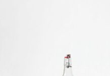 물, 충분히 마시고 있나요? rocks glass beside half empty bottle on white surface