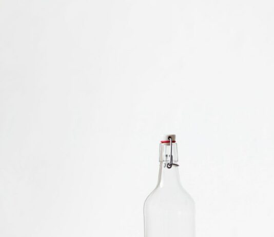 물, 충분히 마시고 있나요? rocks glass beside half empty bottle on white surface