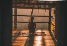명상과 호흡법이 스트레스 해소에 미치는 영향 woman meditating on floor with overlooking view of trees