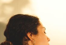 “팔이 찌릿하고 저려요”… 일자목이 아니라 ‘근막통 증후군’일 수도 a woman wearing a white shirt and gold hoop earrings