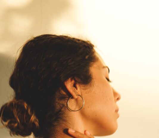 “팔이 찌릿하고 저려요”… 일자목이 아니라 ‘근막통 증후군’일 수도 a woman wearing a white shirt and gold hoop earrings