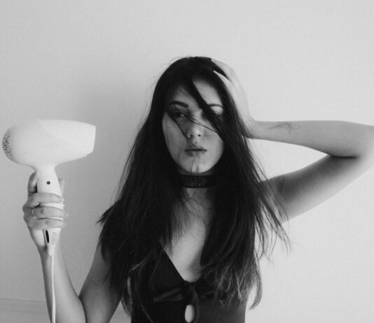 “두피부터 모발까지, 건강하게 지키는 생활 속 헤어 케어 트렌드” woman in black tank top holding her hair