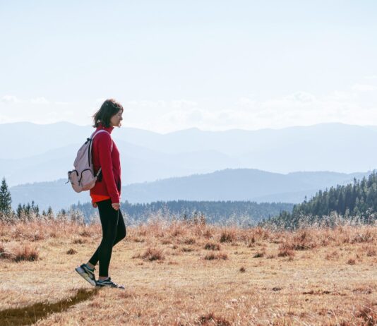 자연 걷기 열풍, 건강한 삶을 위한 실천법 제시 a man with a backpack walking across a dry grass covered field
